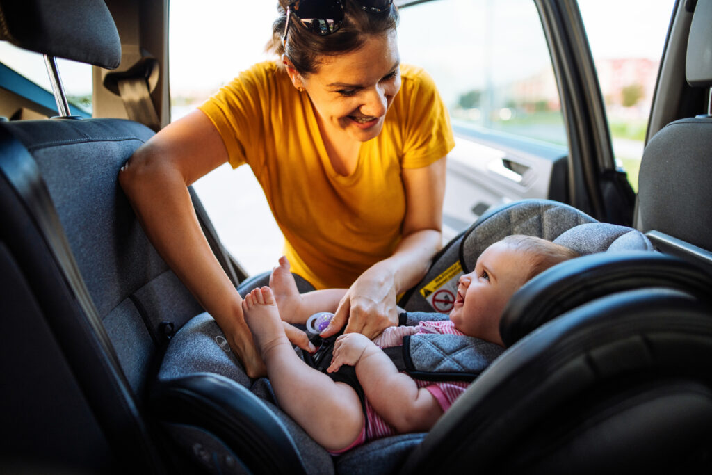 Mother putting a baby in a car seat.